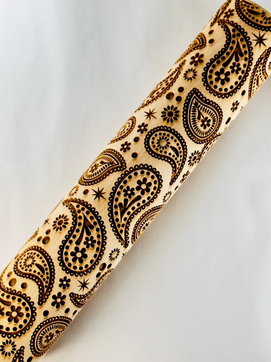 Wooden rolling pin with black paisley pattern on a light gray background