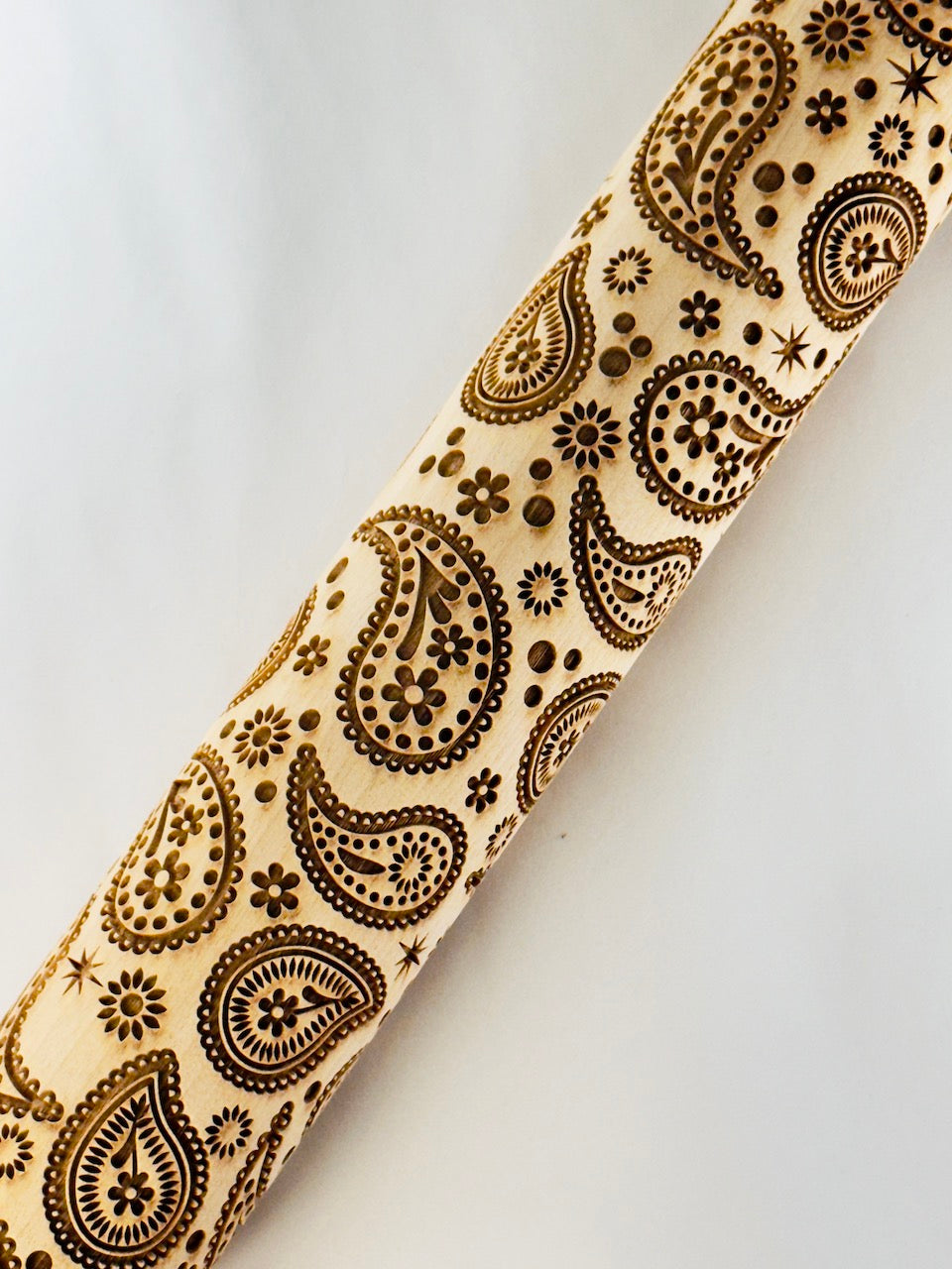Wooden rolling pin with brown paisley pattern on a white background