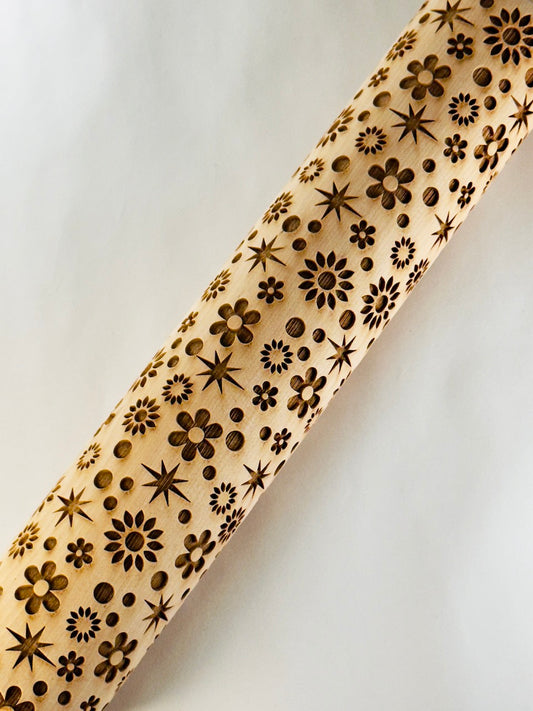 Wooden rolling pin with floral and star patterns on a white background